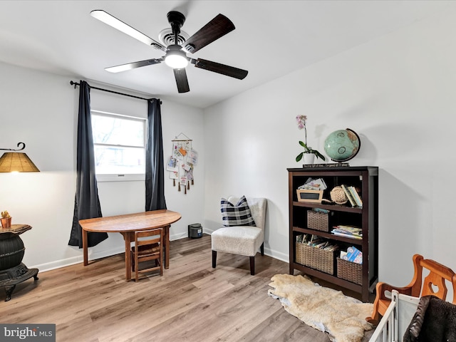 sitting room with baseboards, light wood-type flooring, and a ceiling fan