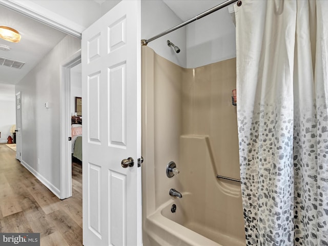 full bath featuring visible vents, connected bathroom, baseboards, shower / bath combo, and wood finished floors