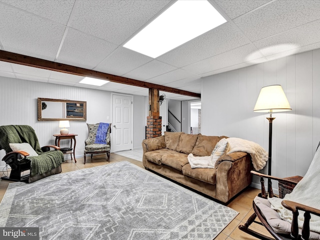 living area featuring light tile patterned floors, a paneled ceiling, and stairs