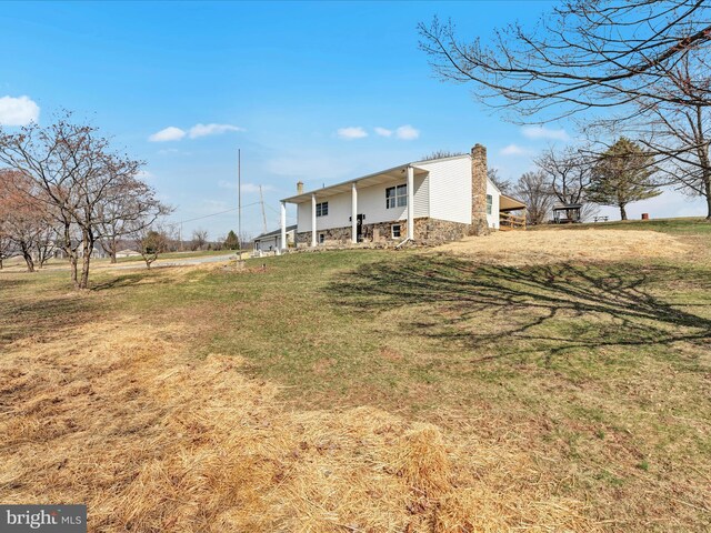 view of front facade with stone siding, a chimney, and a front lawn
