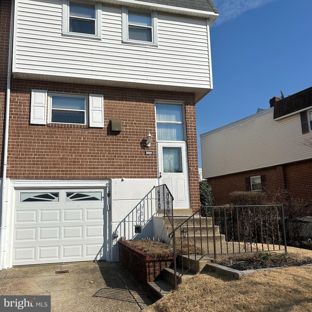 view of front of property featuring driveway, brick siding, and an attached garage