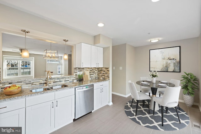 kitchen with a sink, light stone counters, stainless steel dishwasher, white cabinetry, and decorative backsplash