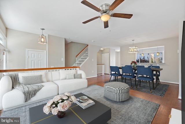 living area featuring stairs, wood finished floors, baseboards, and ceiling fan