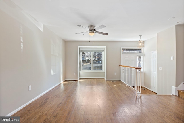 spare room with baseboards, wood finished floors, and a ceiling fan