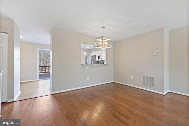 interior space featuring visible vents, baseboards, a notable chandelier, and wood finished floors