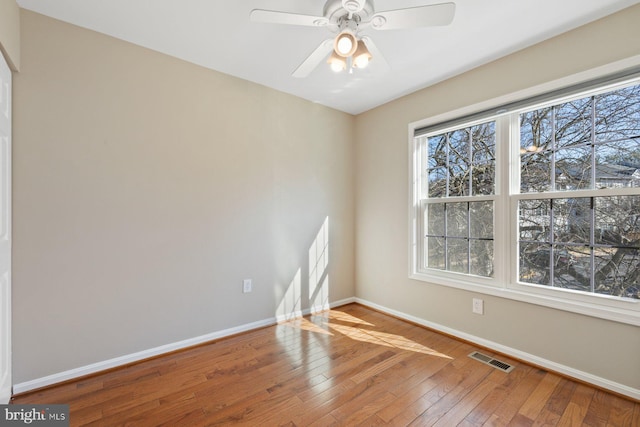 empty room featuring baseboards, visible vents, wood-type flooring, and ceiling fan