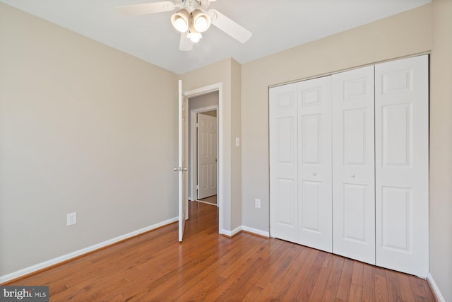 unfurnished bedroom featuring wood finished floors, baseboards, a closet, and ceiling fan