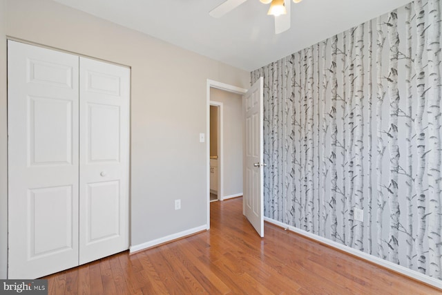 unfurnished bedroom featuring a closet, ceiling fan, baseboards, and wood finished floors