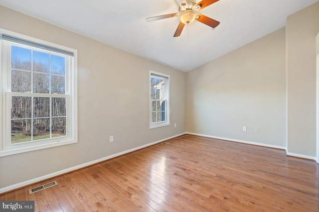 spare room featuring ceiling fan, light wood-style floors, visible vents, and baseboards