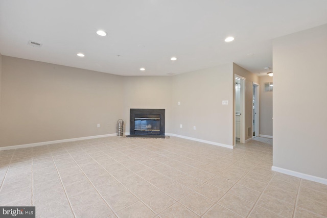 unfurnished living room featuring a glass covered fireplace, visible vents, recessed lighting, and baseboards