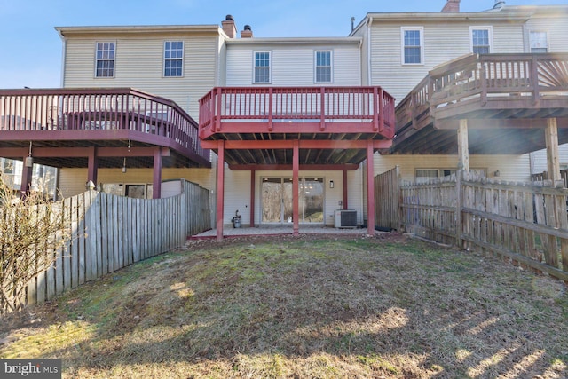 rear view of house featuring a wooden deck, central AC, a chimney, and a fenced backyard