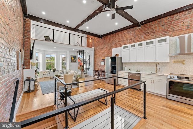 1312 Fairmont St NW Unit 2, Washington, DC 20009 - kitchen featuring stainless steel appliances, brick wall, wall chimney range hood, a sink, and light wood finished floors