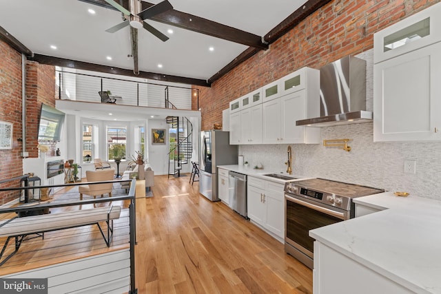 1312 Fairmont St NW Unit 2, Washington, DC 20009 - kitchen with wall chimney range hood, appliances with stainless steel finishes, a sink, a ceiling fan, and white cabinetry