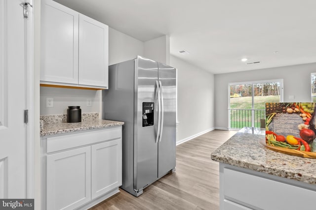 kitchen with light stone countertops, baseboards, light wood-style flooring, stainless steel fridge with ice dispenser, and white cabinets