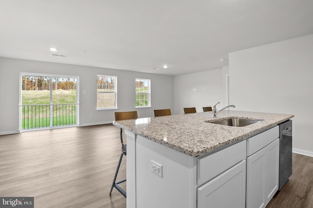 kitchen with a sink, open floor plan, light stone countertops, dishwasher, and dark wood-style flooring