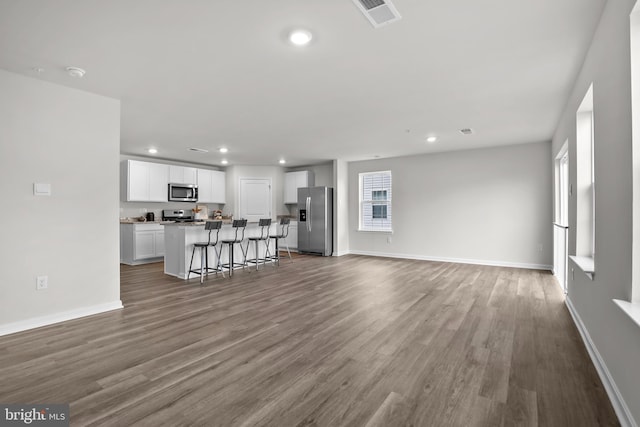 unfurnished living room featuring recessed lighting, wood finished floors, visible vents, and baseboards