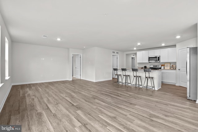 unfurnished living room with recessed lighting, baseboards, visible vents, and light wood finished floors