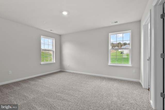 unfurnished bedroom with visible vents, multiple windows, and carpet