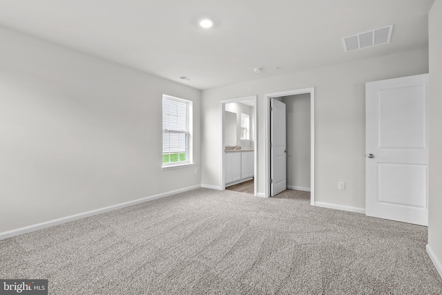 unfurnished bedroom featuring baseboards, visible vents, and light carpet