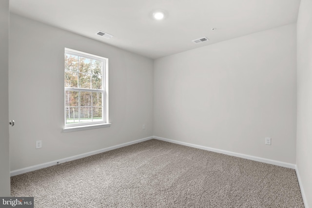 carpeted spare room featuring baseboards and visible vents