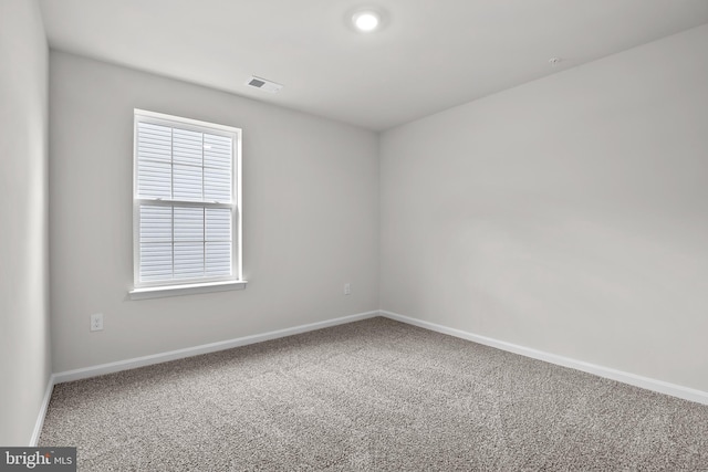 carpeted spare room featuring visible vents and baseboards