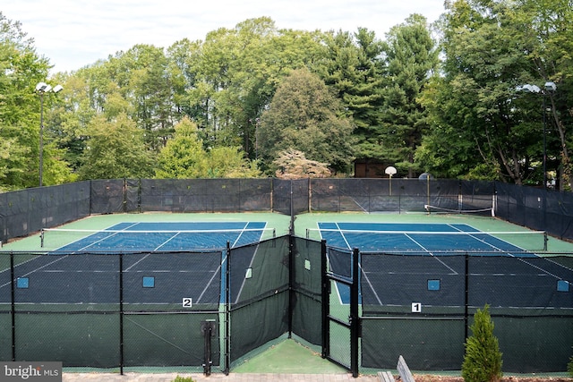 view of tennis court with community basketball court and fence