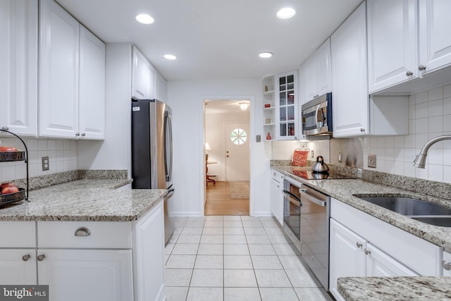 8605 Virginia Ave, Annandale, VA 22003 - kitchen featuring stainless steel appliances, a sink, light tile patterned flooring, white cabinets, and backsplash
