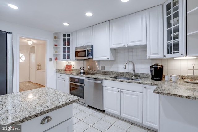 8605 Virginia Ave, Annandale, VA 22003 - kitchen featuring appliances with stainless steel finishes, a sink, light tile patterned floors, and white cabinetry