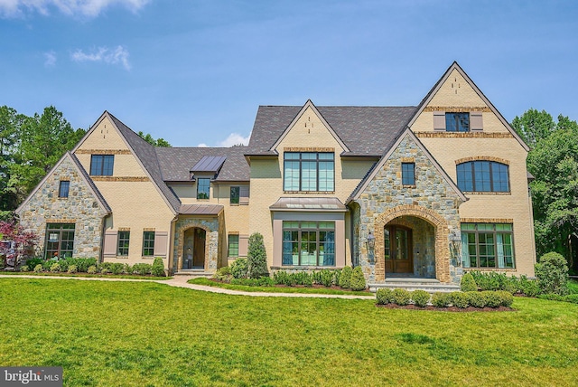 view of front of home with stone siding, a front lawn, metal roof, and a standing seam roof