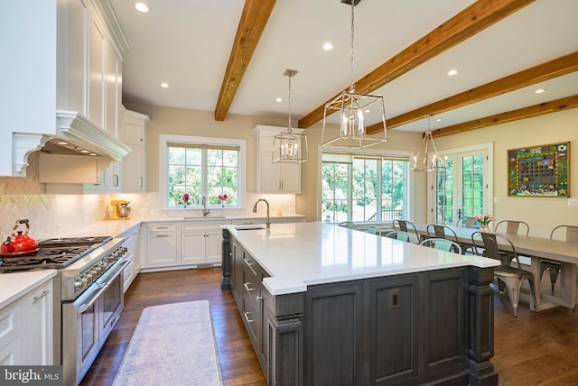 kitchen with a chandelier, light countertops, range with two ovens, white cabinetry, and a sink