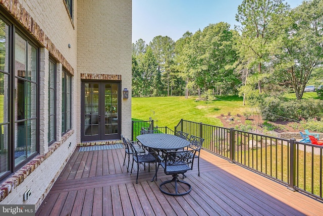 deck featuring outdoor dining area and a yard