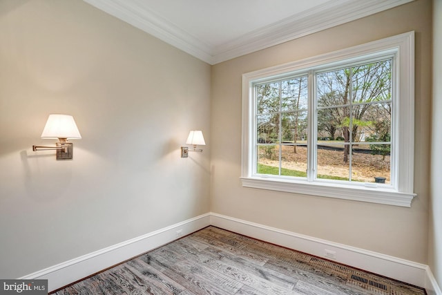 spare room featuring baseboards, plenty of natural light, wood finished floors, and crown molding