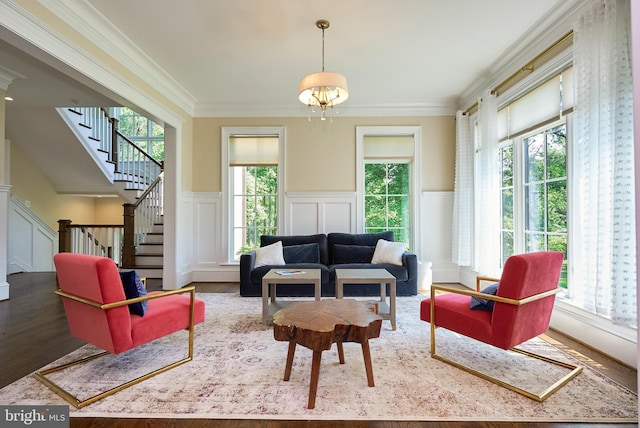 living area with wood finished floors, a wainscoted wall, stairs, crown molding, and a decorative wall