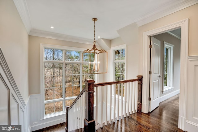 interior space with wainscoting, a notable chandelier, wood finished floors, and crown molding