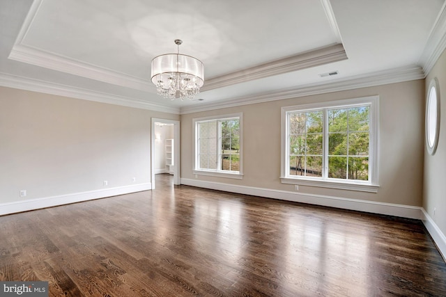 unfurnished room with a tray ceiling, wood finished floors, an inviting chandelier, crown molding, and baseboards