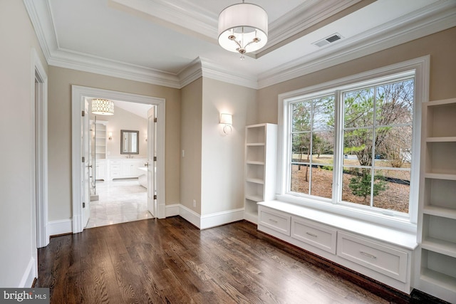 unfurnished dining area featuring visible vents, dark wood-type flooring, a tray ceiling, crown molding, and baseboards