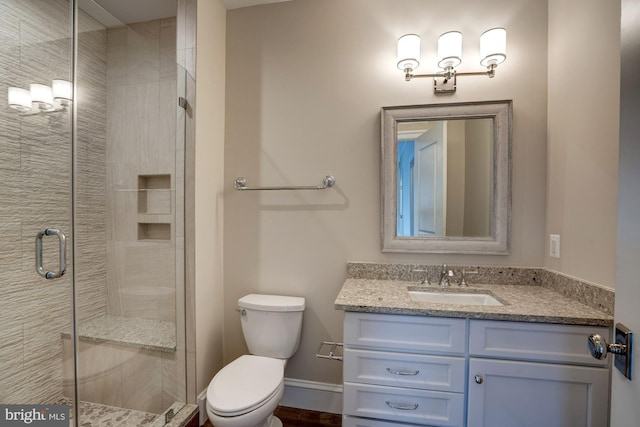 full bathroom featuring baseboards, toilet, a stall shower, and vanity