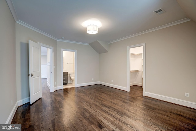 unfurnished bedroom with a spacious closet, visible vents, crown molding, and dark wood-style flooring