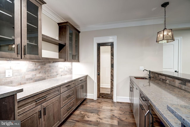 kitchen with a sink, dark wood-style floors, crown molding, decorative backsplash, and dark brown cabinets