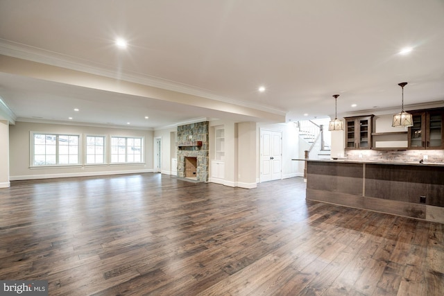 living area with stairway, dark wood-type flooring, baseboards, and ornamental molding