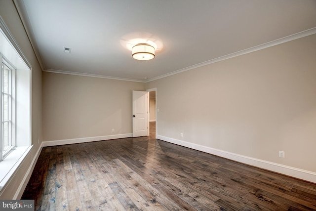 empty room with dark wood finished floors, baseboards, and ornamental molding