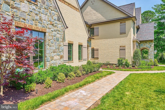 view of home's exterior with stone siding and a lawn