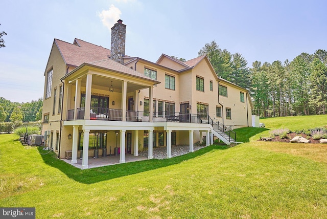 back of property featuring cooling unit, a lawn, a chimney, and a patio area