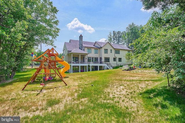 back of property with stairs, a playground, and a yard