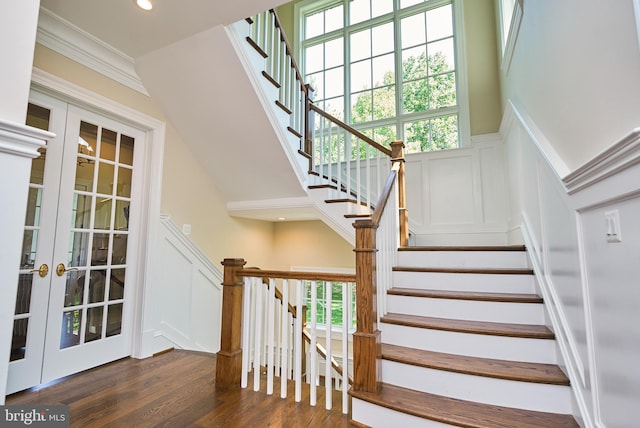 stairs featuring wood finished floors, a wainscoted wall, recessed lighting, french doors, and a decorative wall