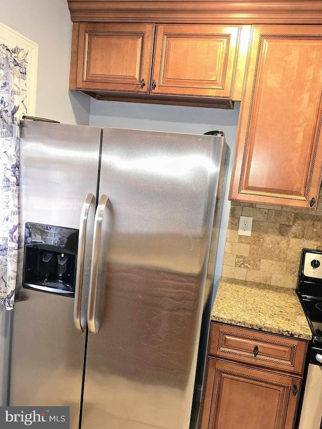 kitchen featuring tasteful backsplash, electric range, brown cabinets, and stainless steel refrigerator with ice dispenser