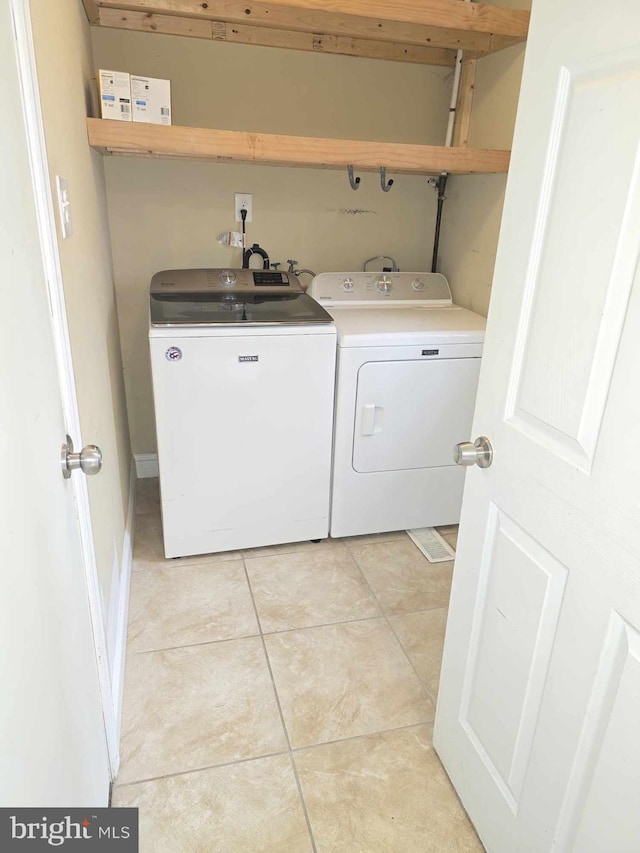 laundry area with laundry area, light tile patterned floors, and washing machine and dryer