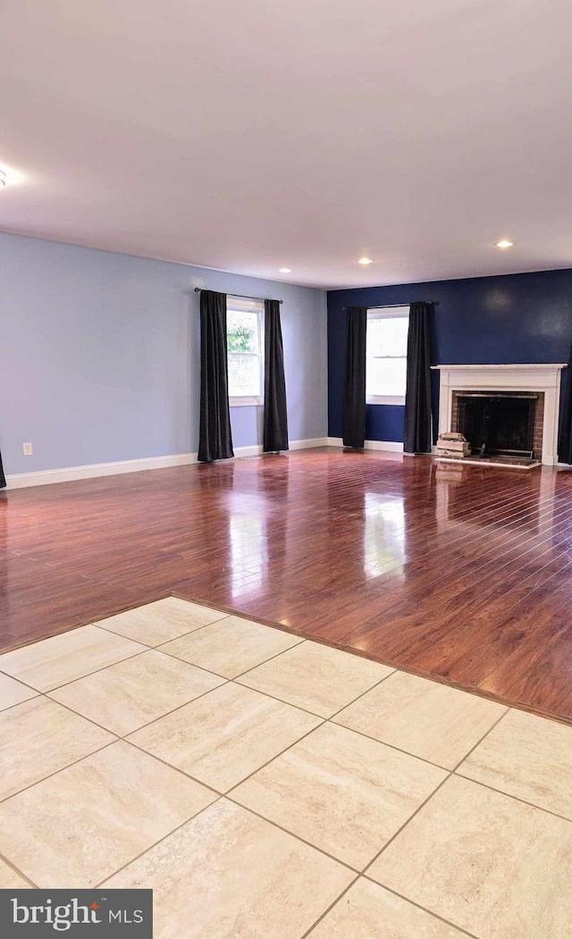 unfurnished living room featuring a fireplace, recessed lighting, wood finished floors, and baseboards