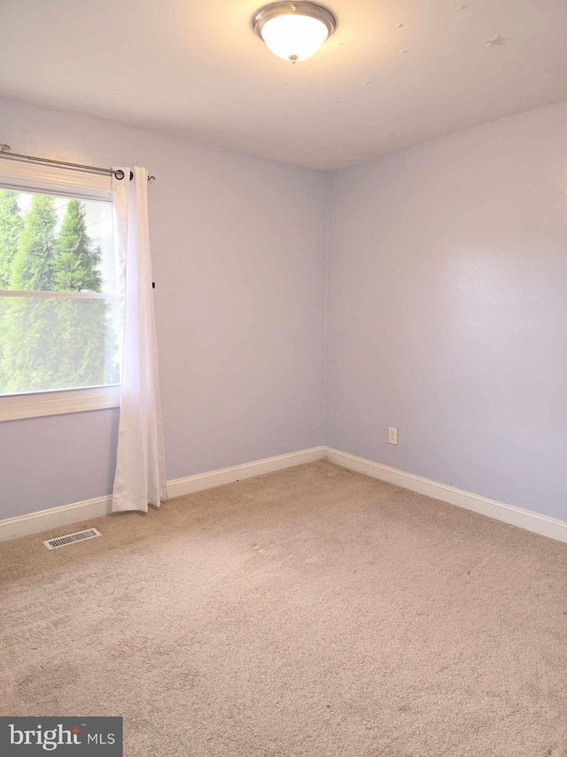 carpeted spare room with visible vents and baseboards