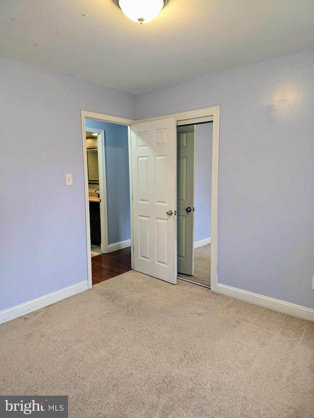 unfurnished bedroom with a closet, carpet flooring, and baseboards